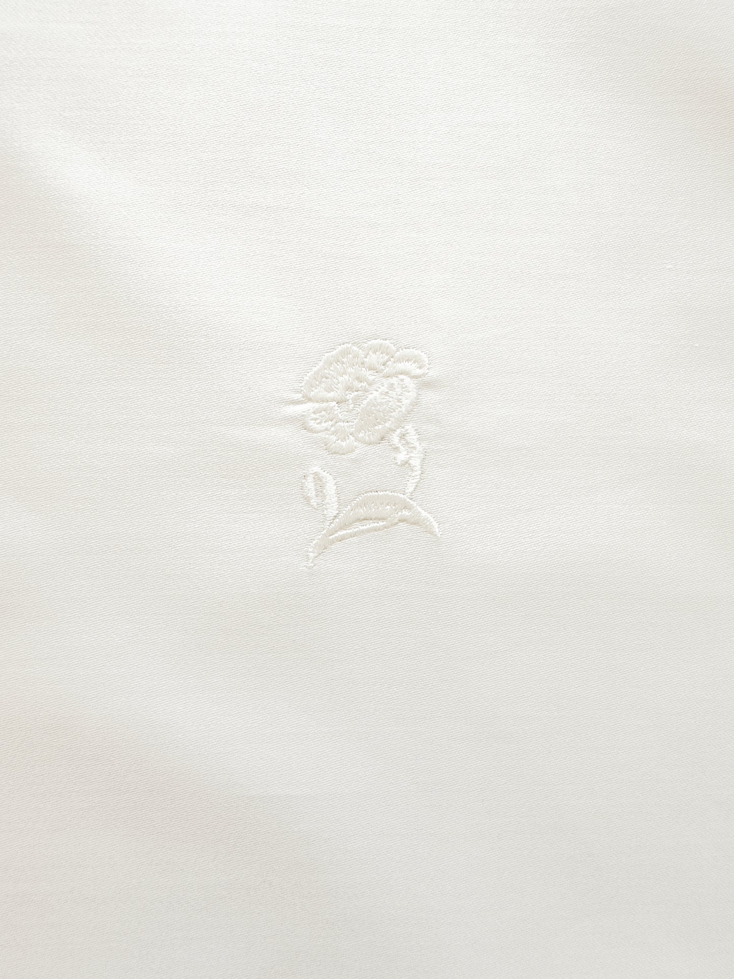 White fabric with a subtle floral pattern on a white background