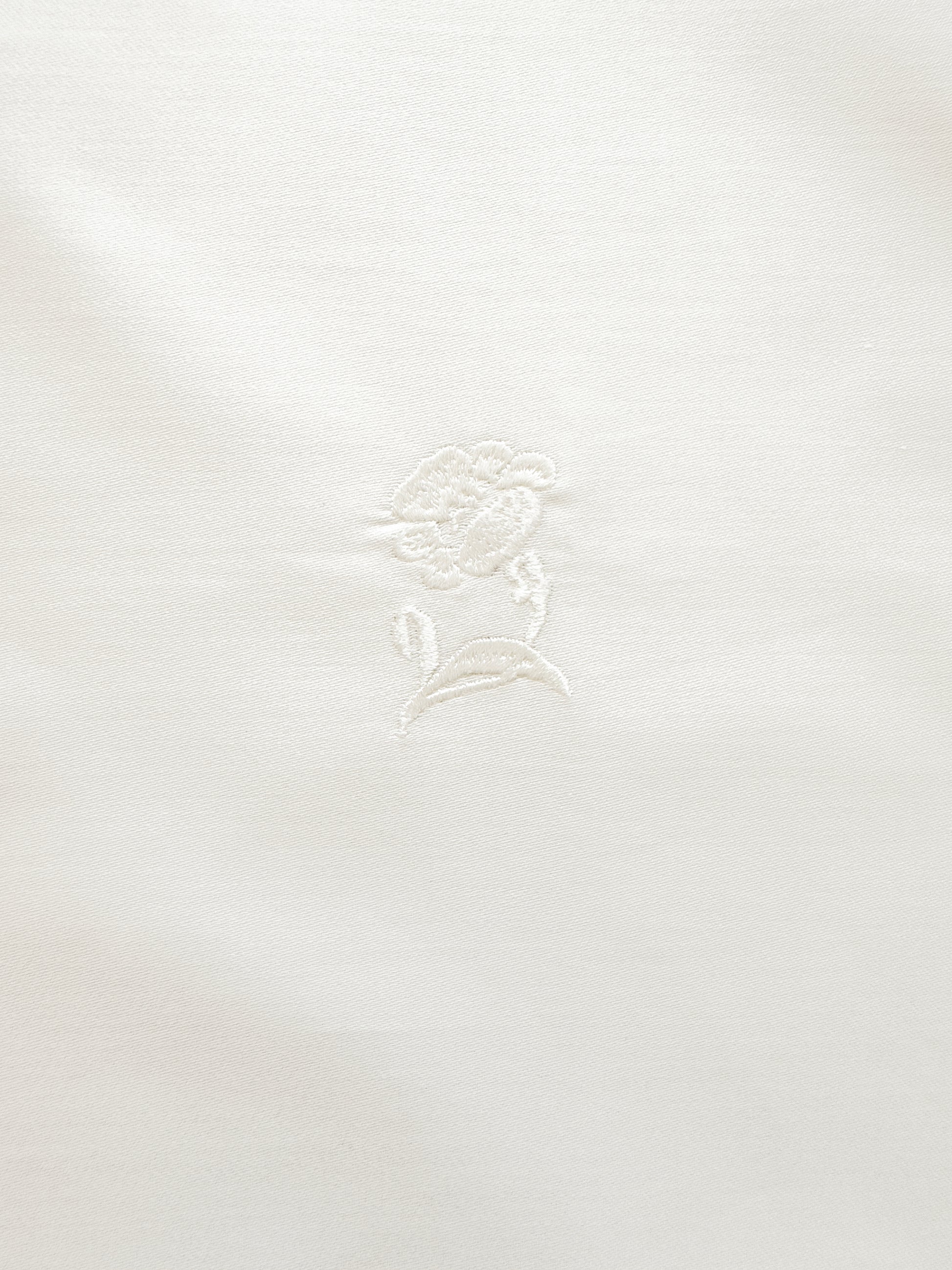 White fabric with a subtle floral pattern on a white background