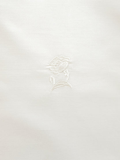 White fabric with a subtle floral pattern on a white background