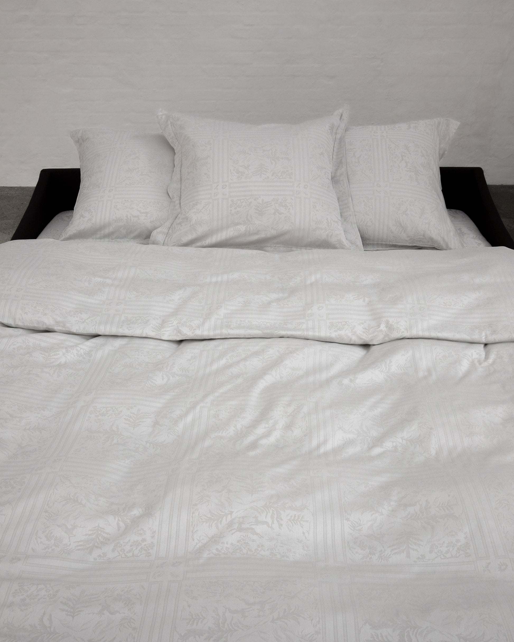 Gray textured bedding set on a bed with a neutral background
