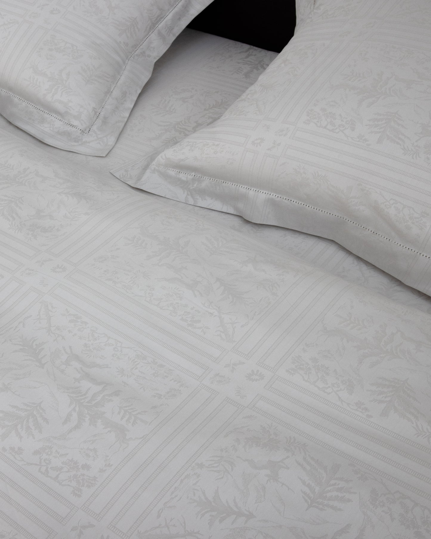 Gray textured bed sheets with folded edges on a black background