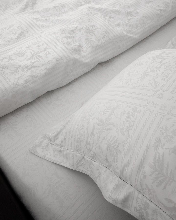 Close-up of white textured bed sheets and pillowcases.