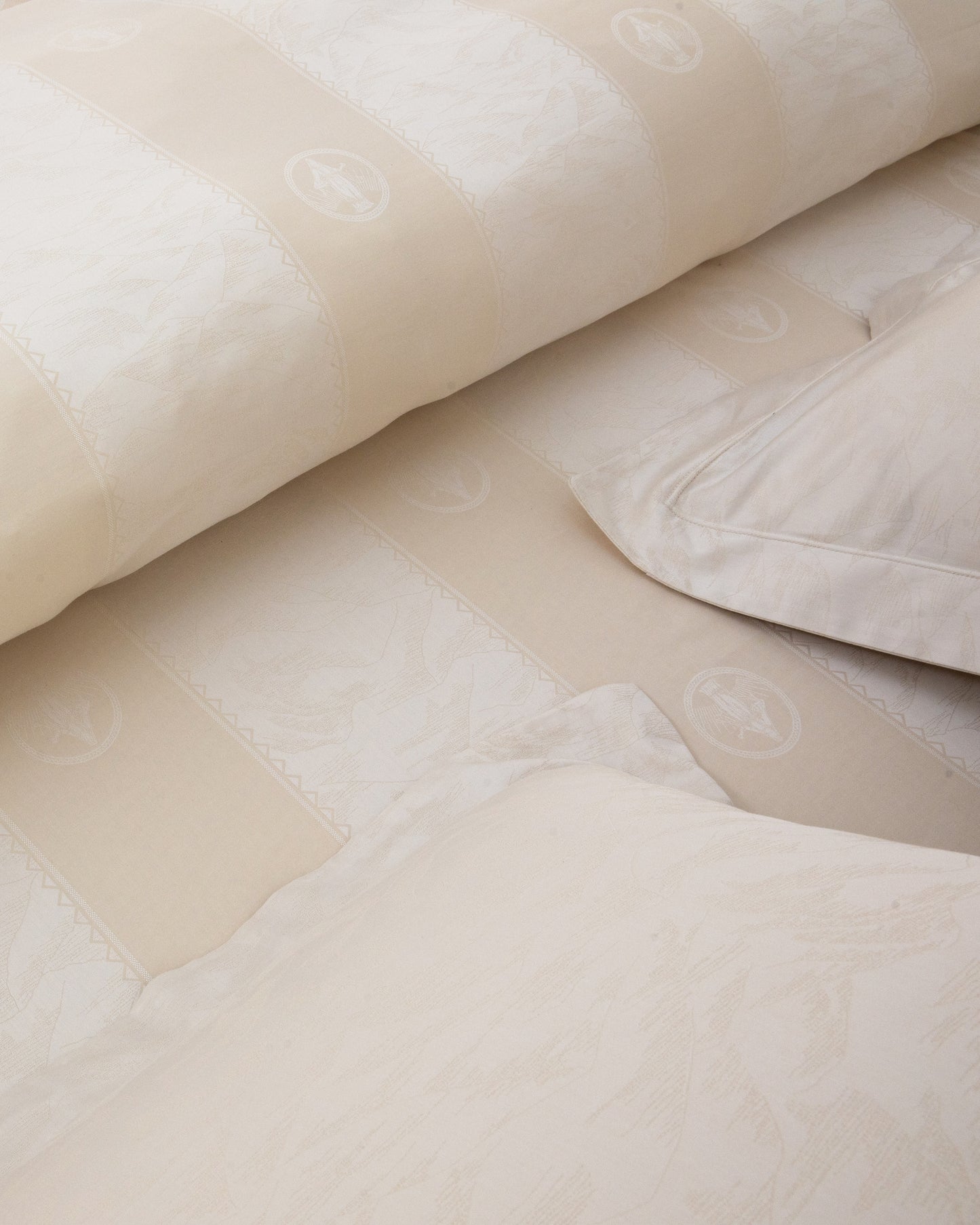 Close-up of beige textured fabric with a pillow and blanket on a surface.