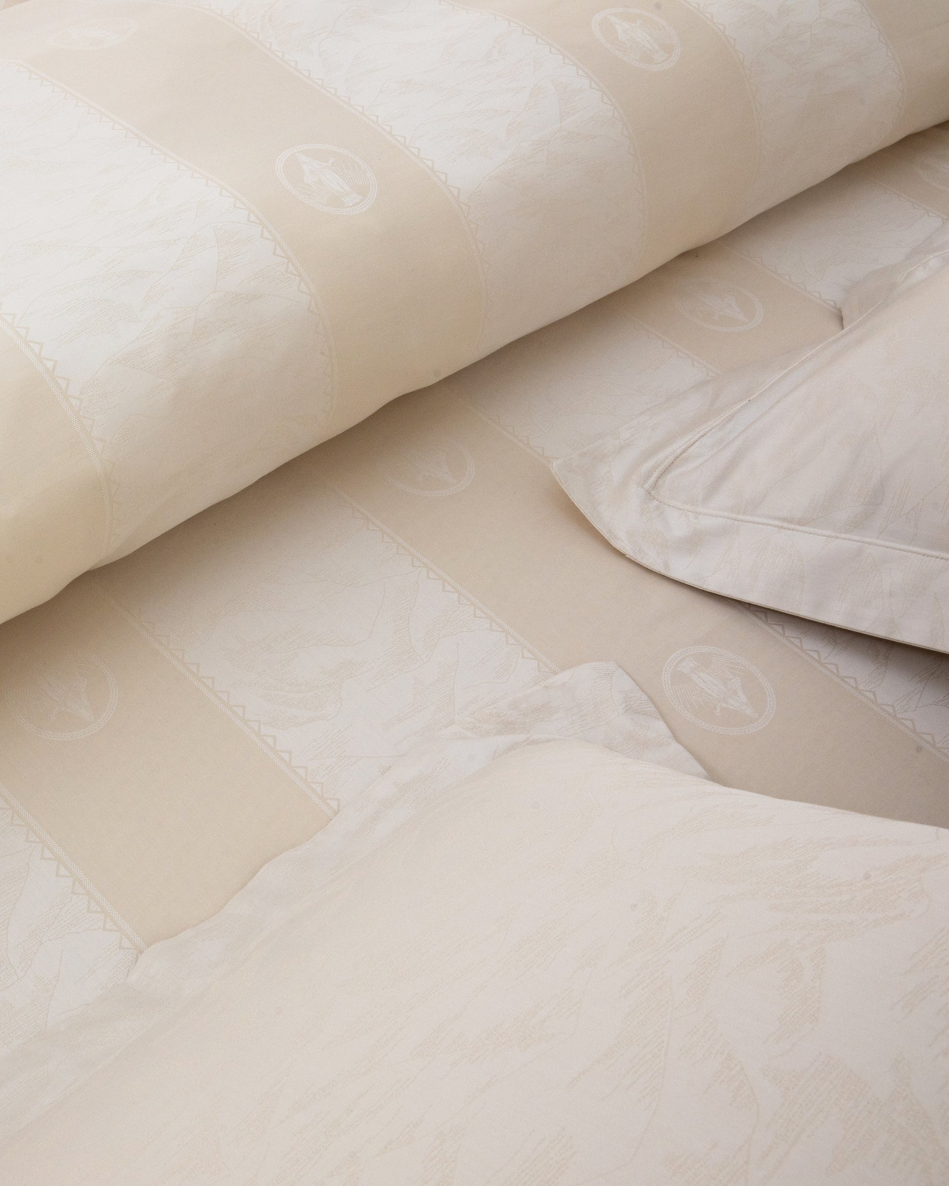 Close-up of beige textured fabric with a pillow and blanket on a surface.