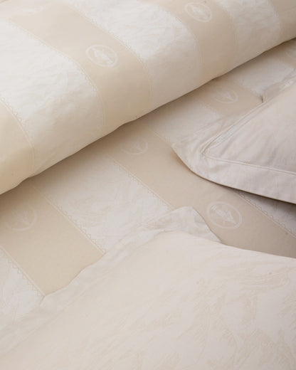 Close-up of beige textured fabric with a pillow and blanket on a surface.